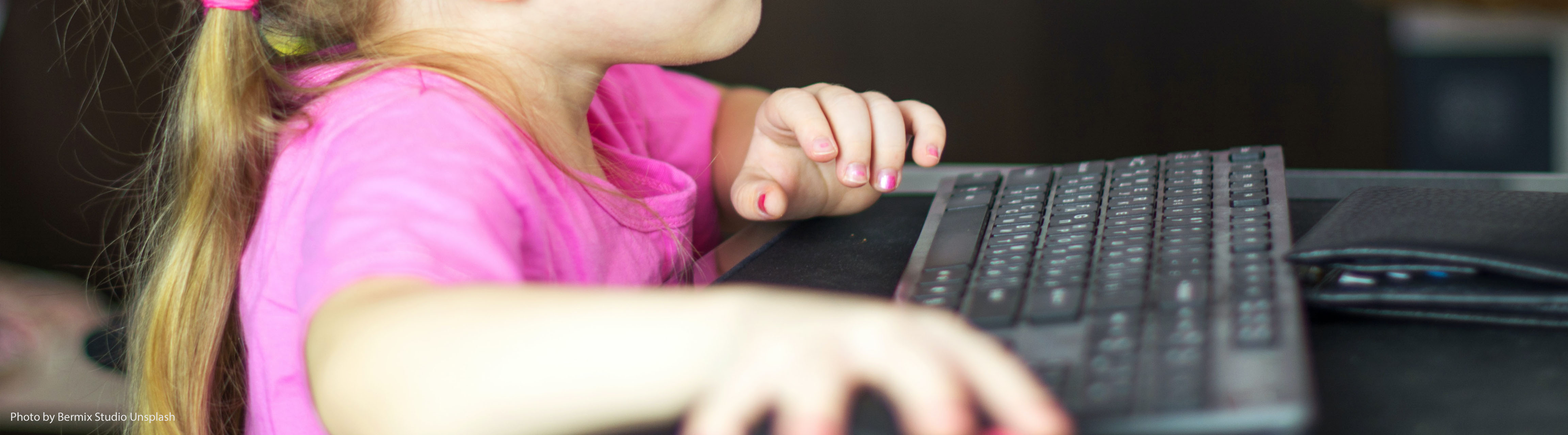 Mädchen in rosa T-Shirt sitzt vor einem Computer und bedient die Maus, "Gewalt und Geschlechterrollen in Computerspielen", ZIMD