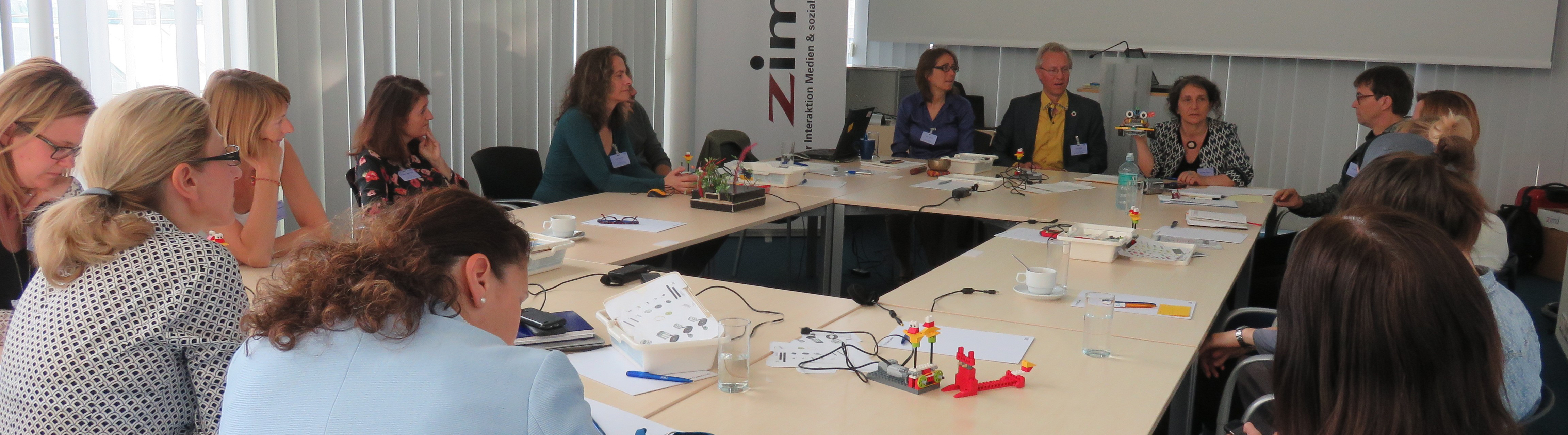 Dorothea Erharter und TeilnehmerInnen des Innovationslabor Gender & Technik sitzen an einem großen Tisch zusammen, ZIMD