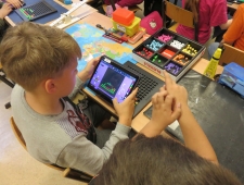 Zwei Buben arbeiten mit Tablet und ihrem "Bloxels"-Bausatz aus bunten Steinen und einem schwarzen Spielfeld. "Bloxels", ZIMD