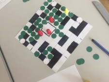 Game Design, ZIMD Foto eines quadratischen Spielbrettes mit schwarzen, weißen, grünen und roten Spielsteinen, "Game Design", ZIMD