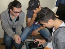 Pocketcode, ZIMD Drei jugendliche Burschen sitzen im Kreis. Ein Bursch zeichnet eine Grafik mit dem Finger auf dem Tablet, "Pocketcode", ZIMD