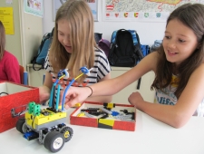 Drei Mädchen bauen an ihrem buntene Roboter und lächeln, "Roberta", ZIMD