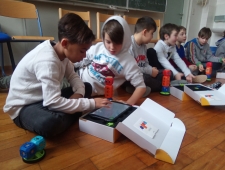 Eine Gruppe Buben sitzen auf dem Boden und programmieren ihre Roboter mit Tablets, "Robo Wunderkind", ZIMD