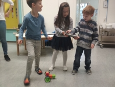 Zwei Buben und ein Mädchen beobachten den selbst gebauten Roboter, der vor ihnen steht. Das Mädchen steuert ihn vom Tablet aus. "Robo Wunderkind", ZIMD