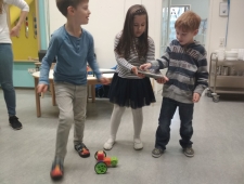 Robo Wunderkind, ZIMD Zwei Buben und ein Mädchen beobachten den selbst gebauten Roboter, der vor ihnen steht. Das Mädchen steuert ihn vom Tablet aus. "Robo Wunderkind", ZIMD